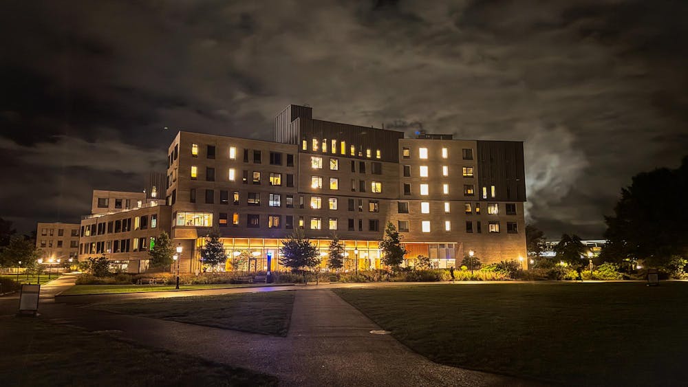 A light brown building with some windows lighted at night.