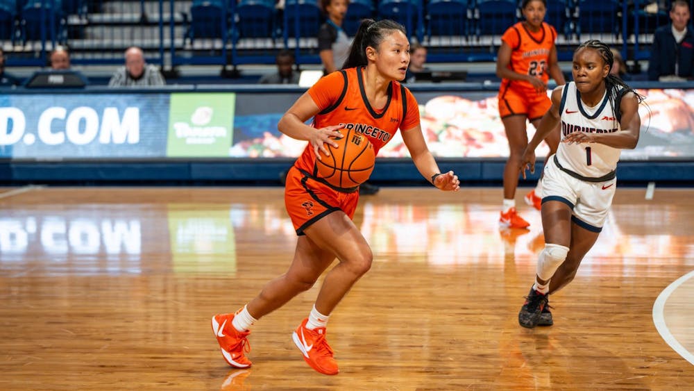 person in orange basketball jersey and orange shoes with long ponytail dribbles basketball