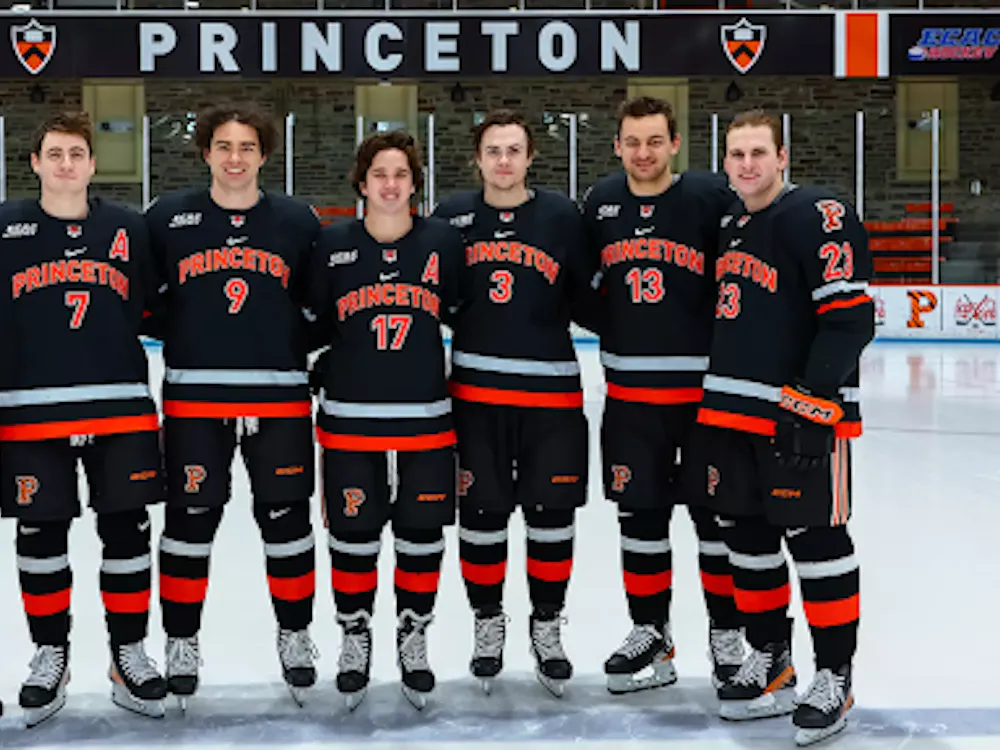 Seven hockey players in black and orange jerseys face the camera.