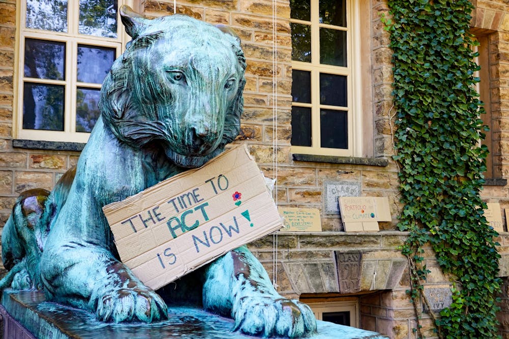 Tiger statue with cardboard sign reading "the time to act is now."