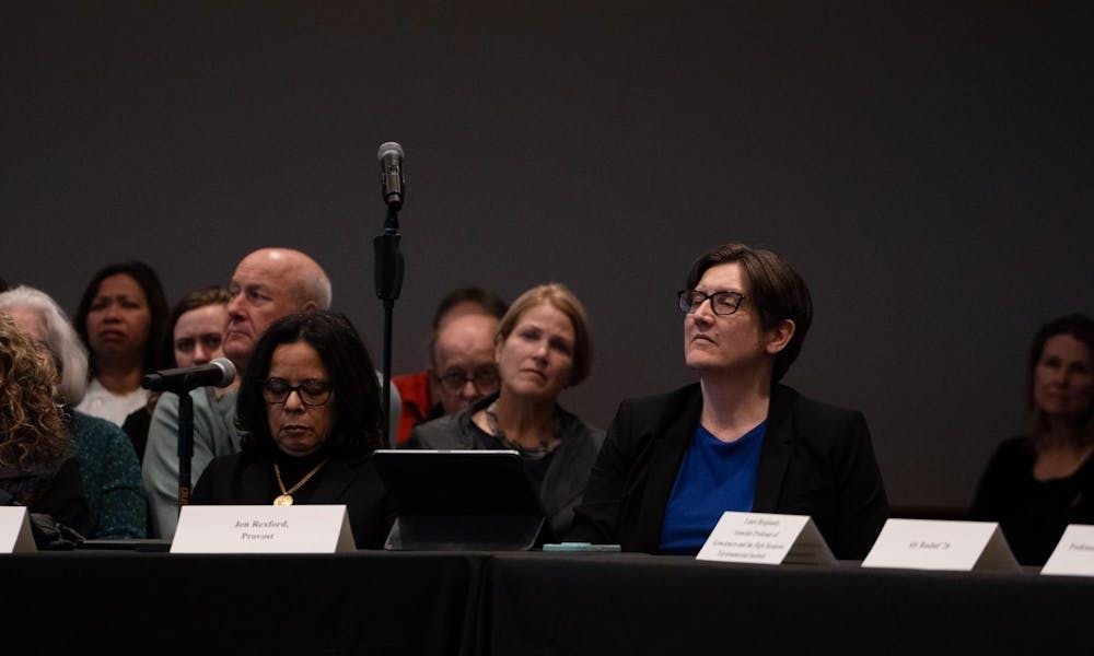 Una mujer sentada en una mesa con un cartel delante de ella en una reunión.