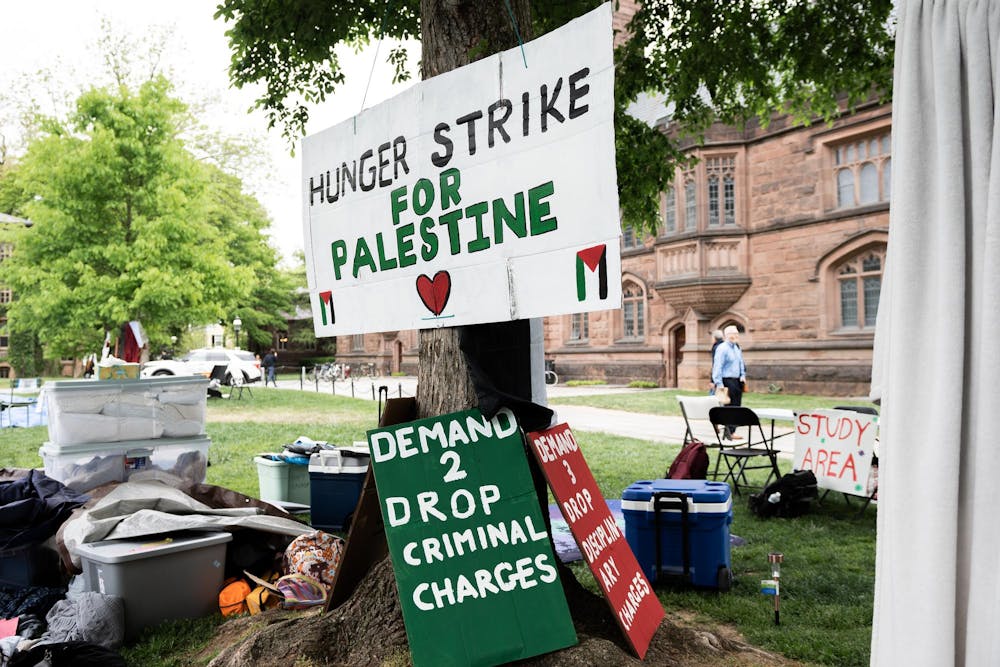 A white sign posted to a tree reads "hunger strike for Palestine."