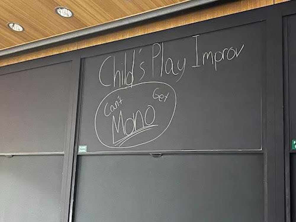 A black chalkboard the phrases "Child's Play Improv" and "Can't Get Mono" written in white chalk. 