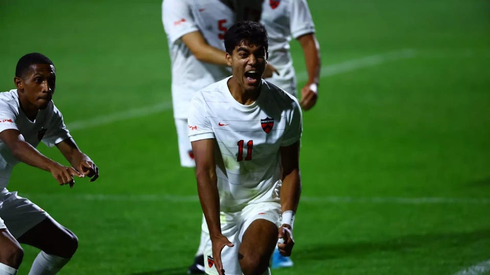 A man in a white uniform celebrating during a soccer game. 