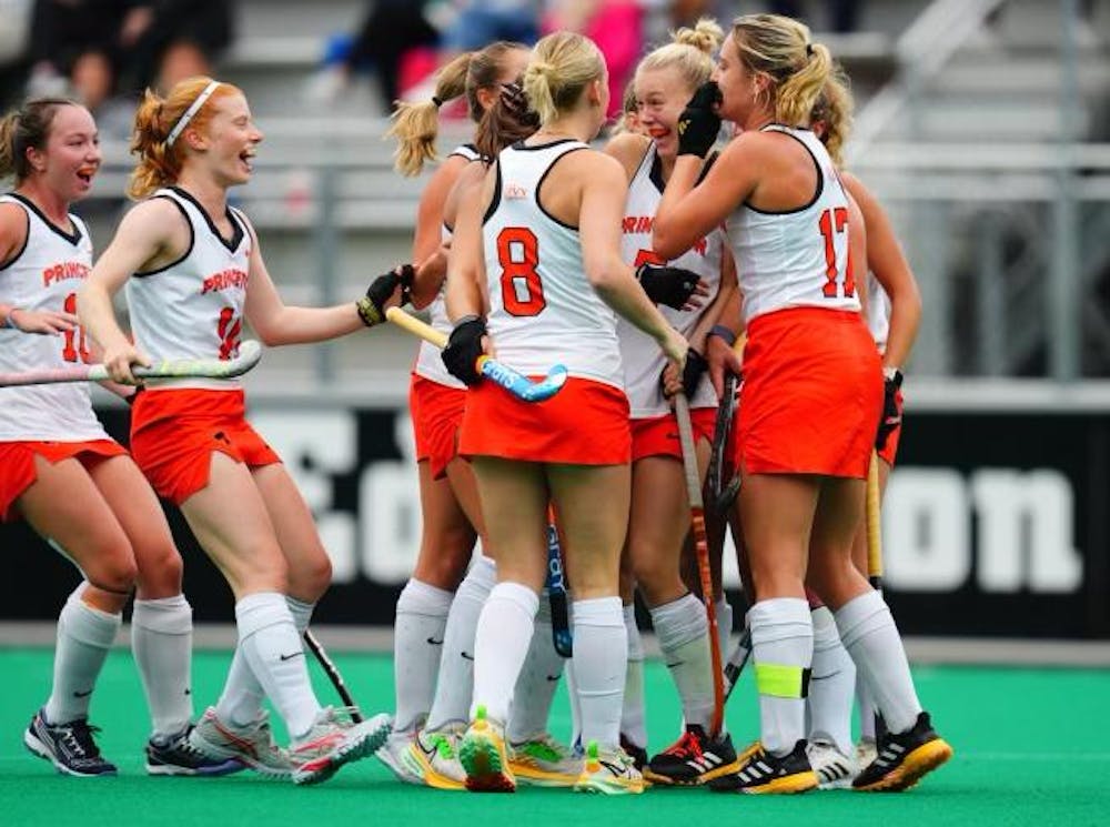 A group of players in orange and white uniforms celebrate in a huddle after goal.