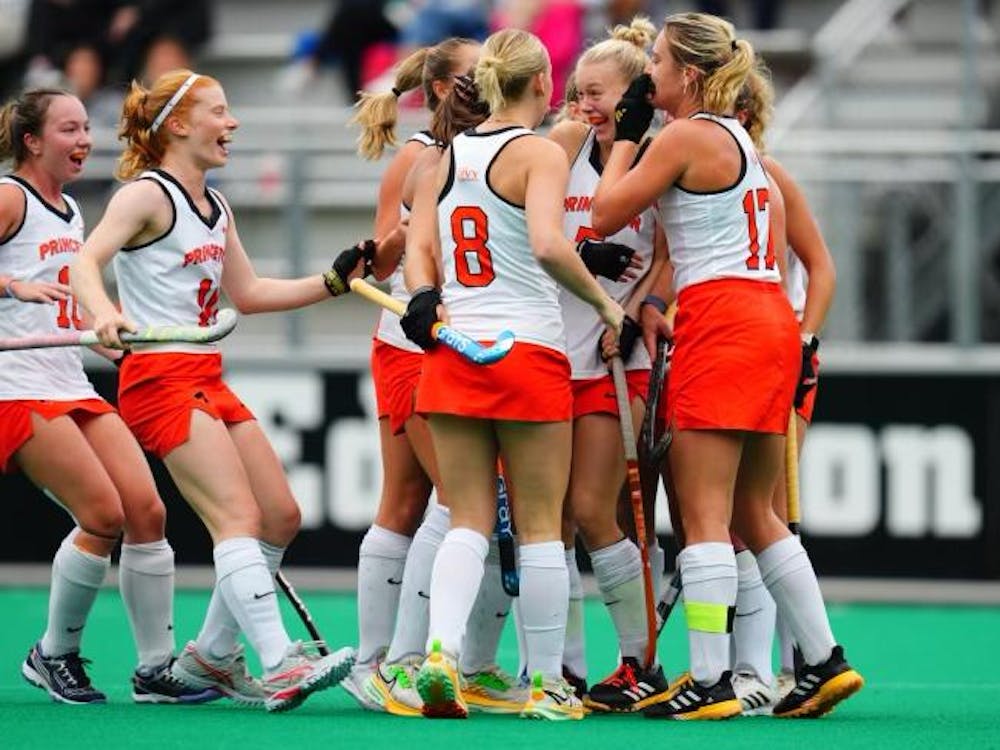 A group of players in orange and white uniforms celebrate in a huddle after goal.