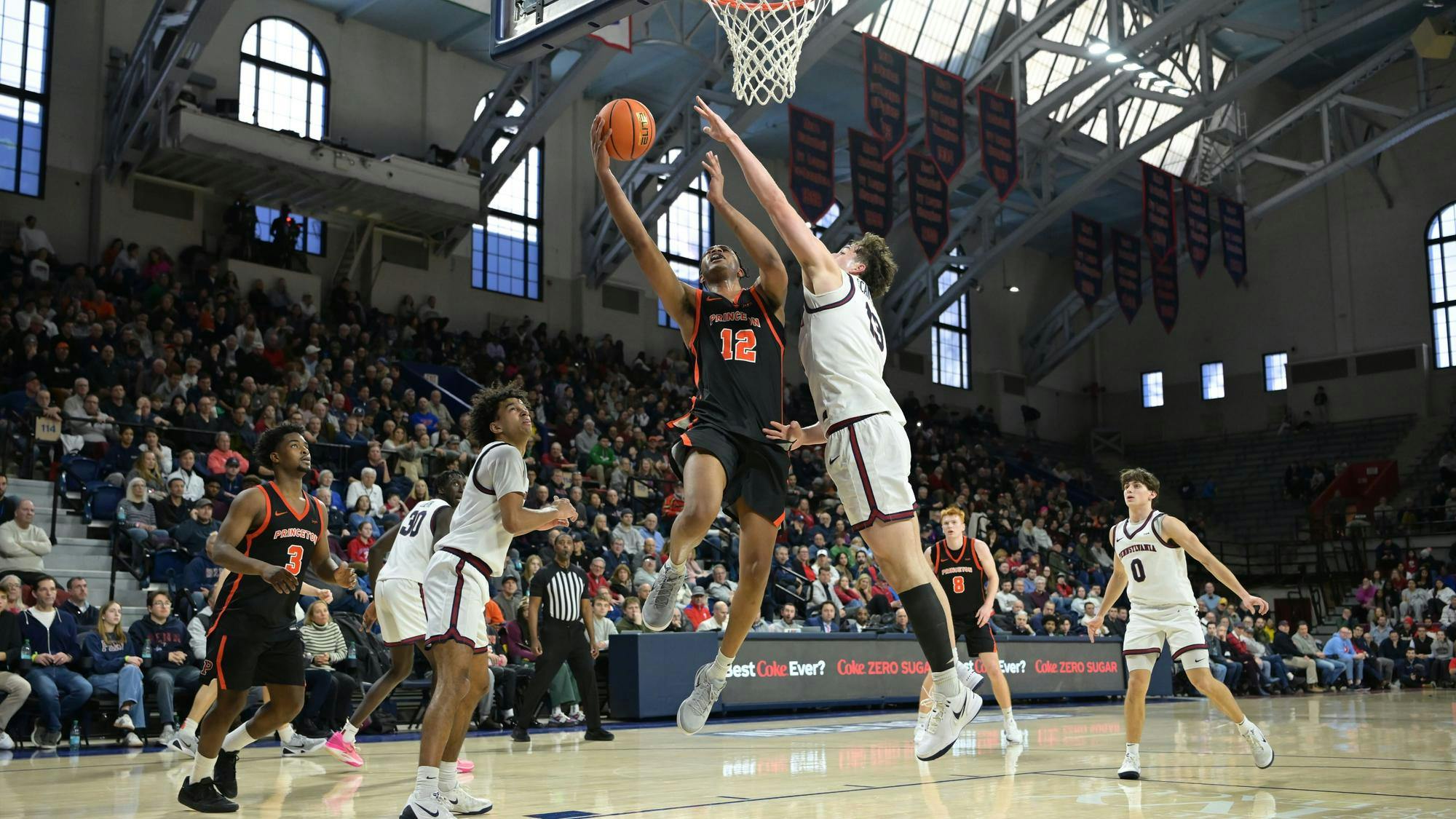 Princeton men's basketball player shoots a contested layup against Penn men's basketball player. 