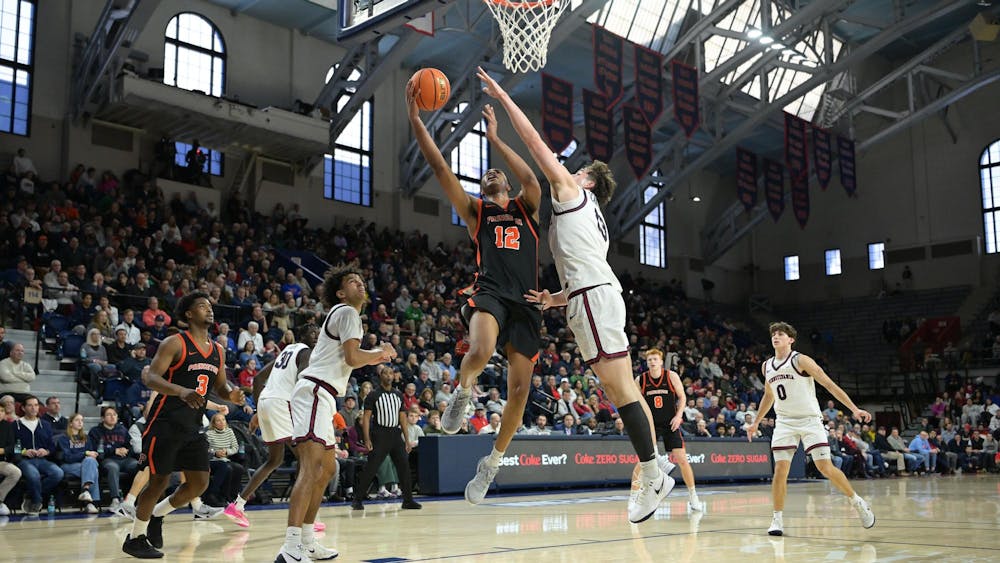 Princeton men's basketball player shoots a contested layup against Penn men's basketball player. 