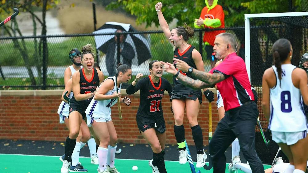 Princeton players in black uniforms cheer and one of the players jumps in the air pumping her fist.
