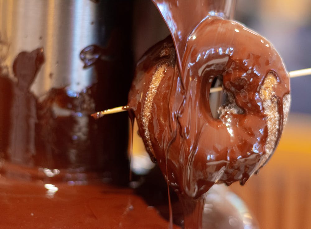 &nbsp;A donut is dipped into a chocolate fountain.&nbsp;