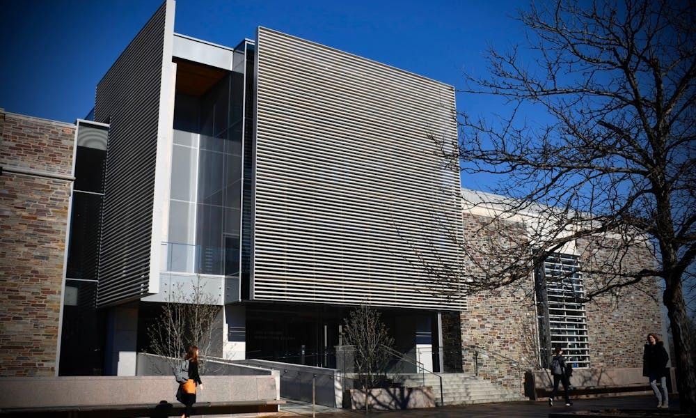 A large gray metallic building stands behind the silhouette of a leafless tree.