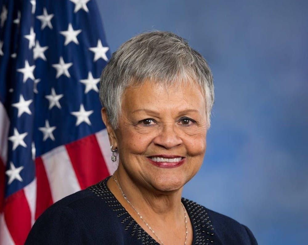 Una foto de la representante estadounidense Bonnie Watson Coleman sonriendo frente a una bandera estadounidense sobre un fondo azul.