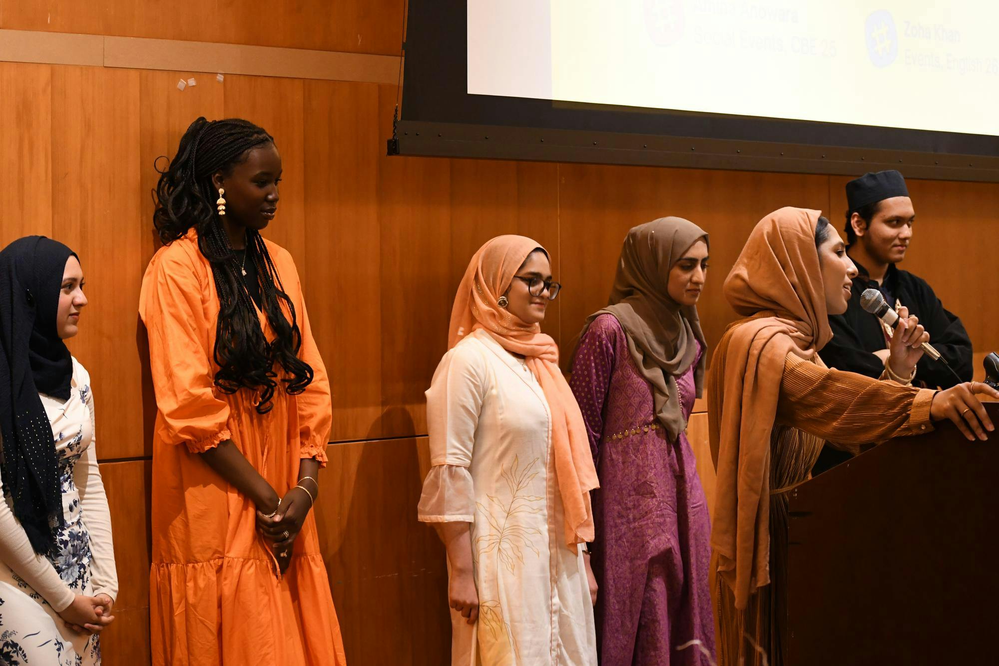 Several students in the Muslim Students Association are standing by the podium while one speaks to the audience.