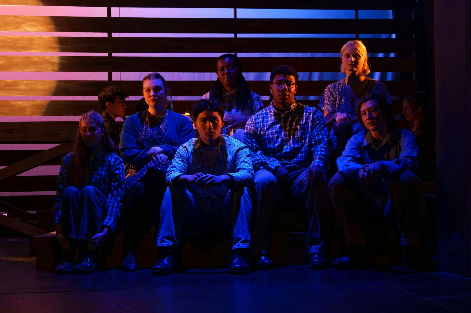 Several students sit together in dark stage lighting.