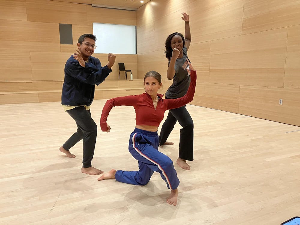 Three people pose in a dance studio.