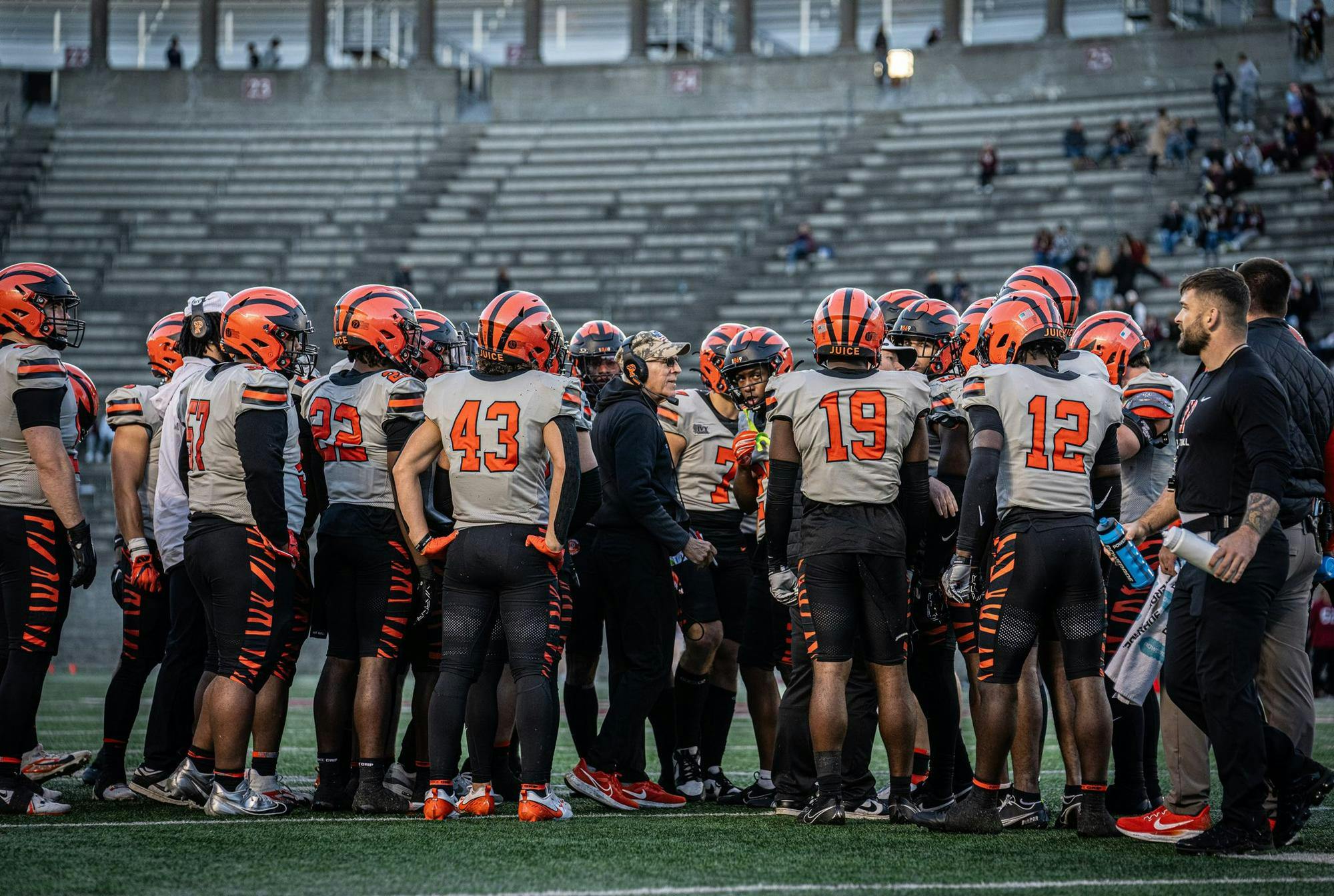 Football team in grey jerseys huddle up.