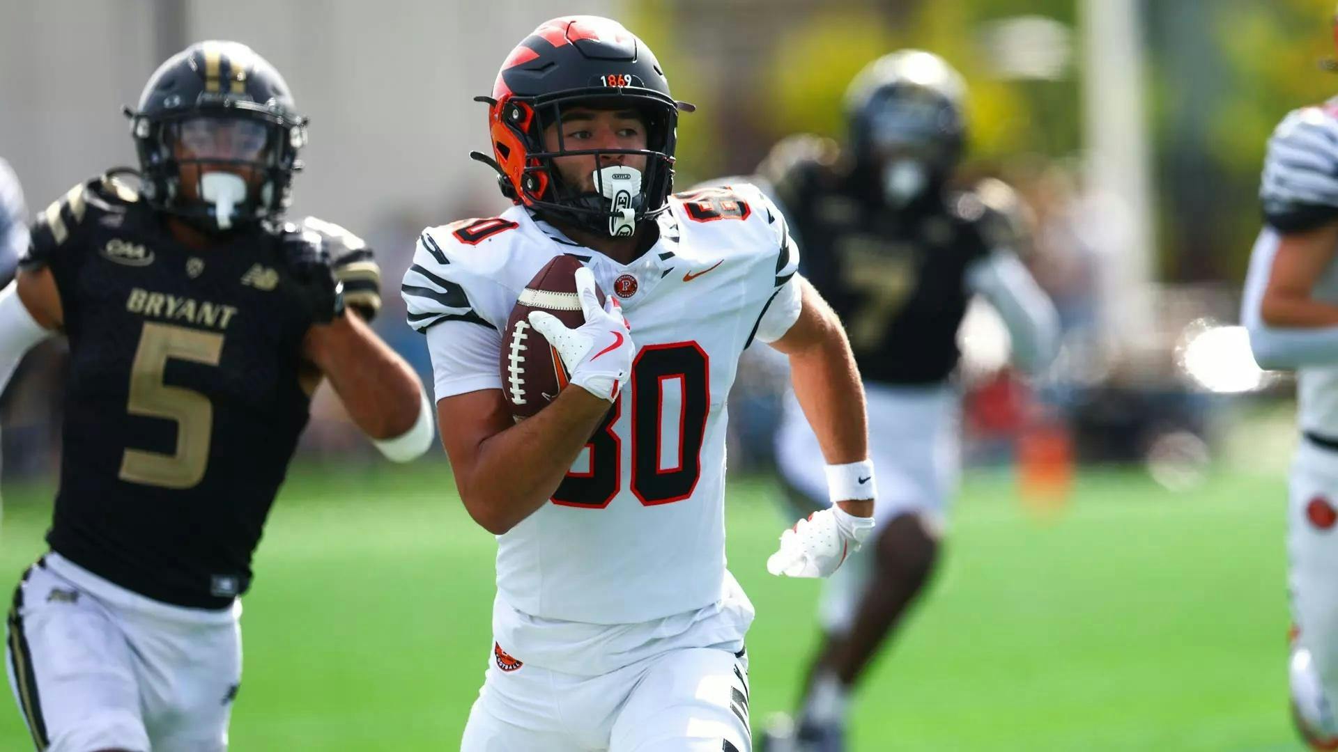 Player in white jersey holds football and runs.