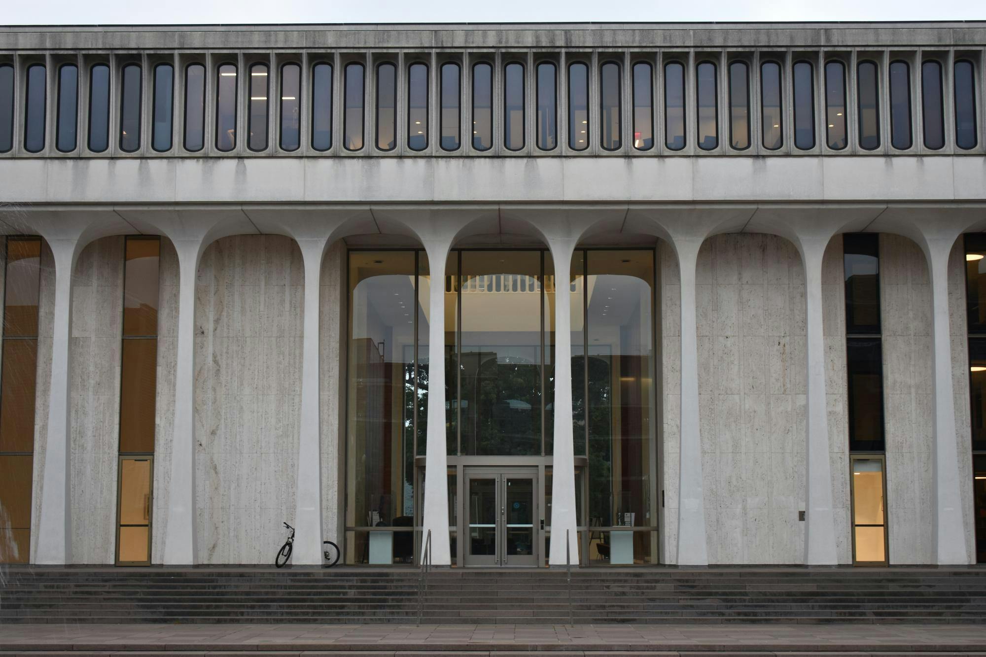 The front of a white building, with columns, a gray door, and a large window