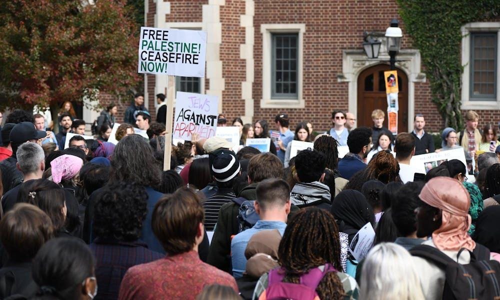 Un grupo de personas está de espaldas a la cámara. Algunas sostienen carteles que dicen "¡Palestina libre! ¡Alto el fuego ya!" y "Judíos contra el apartheid".
