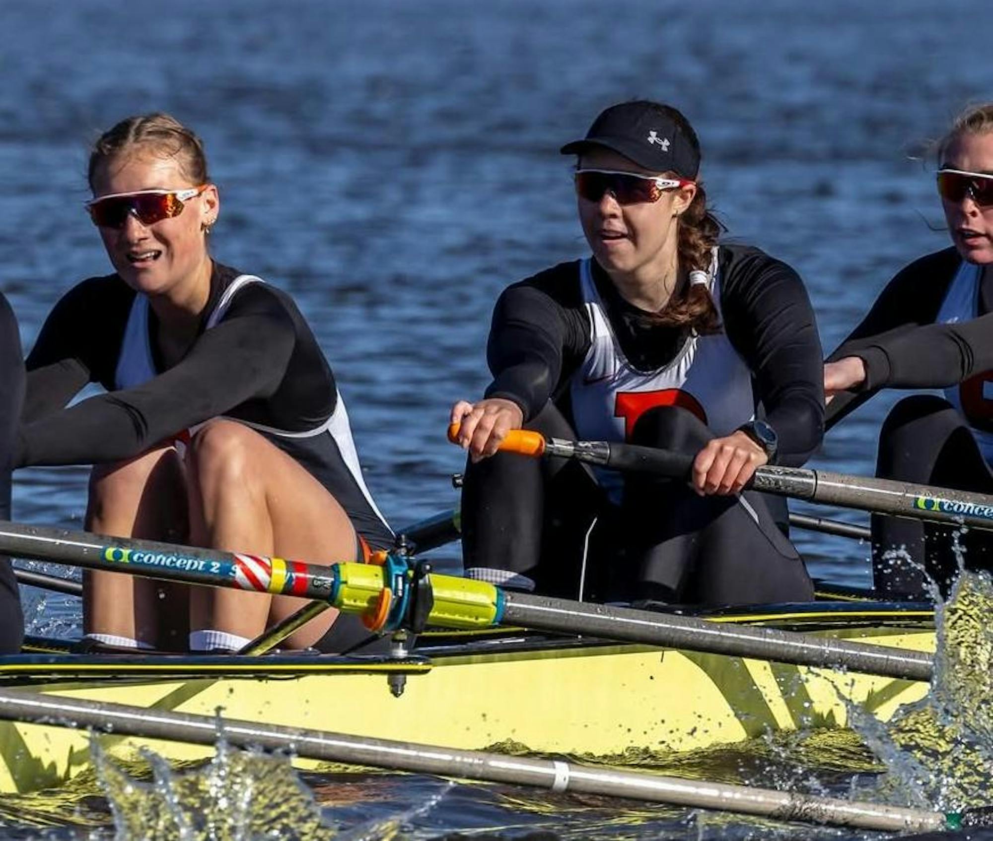 A woman wearing colorful knee-high socks and old-fashioned visors while rowing on a boat.