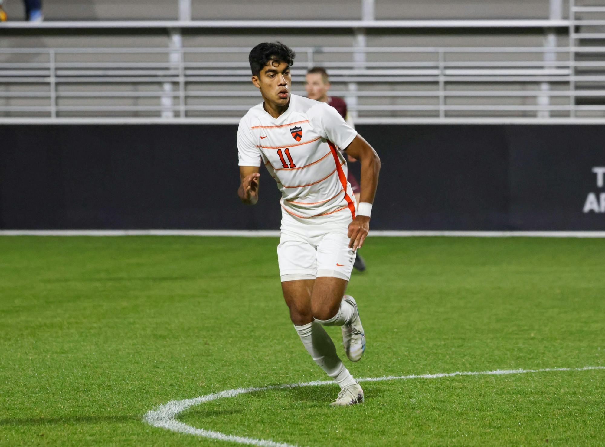 A player wearing a white kit jogging on a soccer field. 