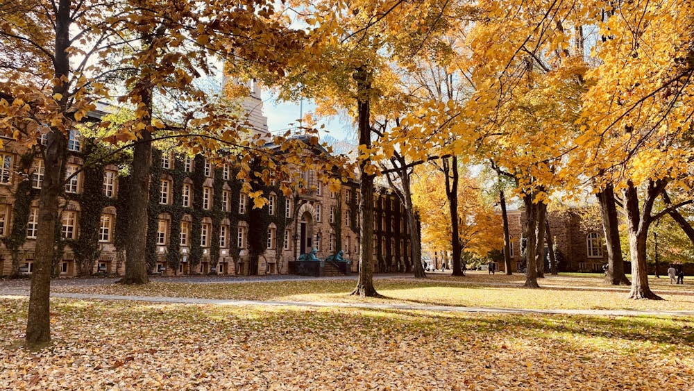 Beige building with ivy covering it. Trees with yellow leaves surround the building.