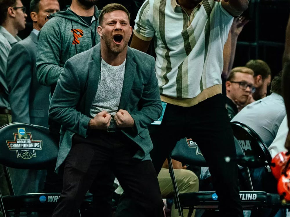 Coaches in grey cheering and yelling with black chairs in back.