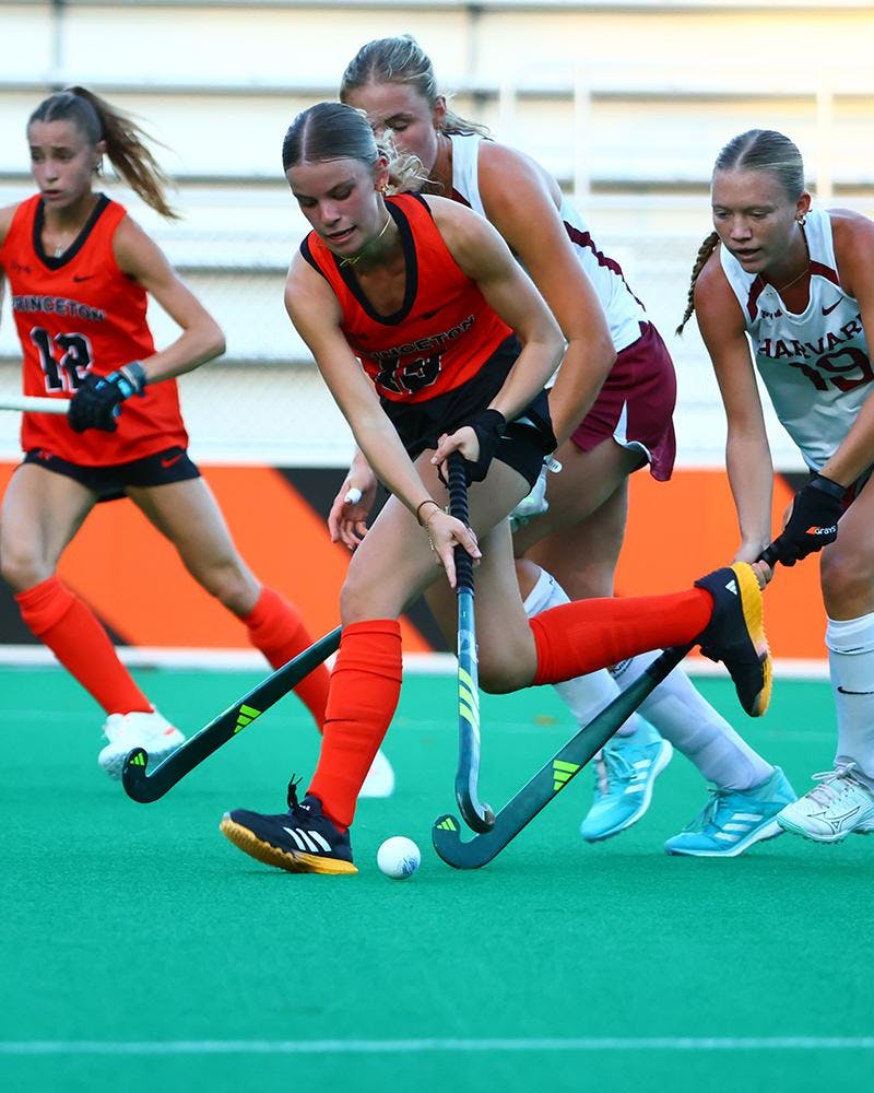Field hockey players running with ball.