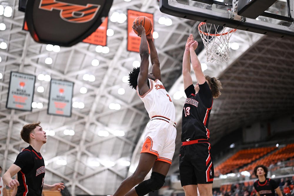 A Princeton men’s basketball player rises for a shot at the rim as a Northeastern defender contests it.