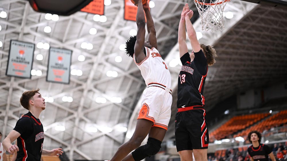 A Princeton men’s basketball player rises for a shot at the rim as a Northeastern defender contests it.