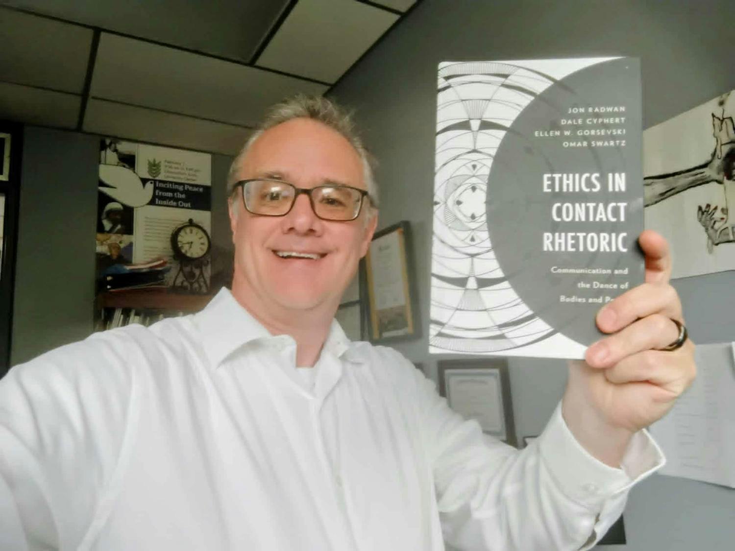 Dr. Radwan holds up his new book, "Ethics in Contact Rhetoric."