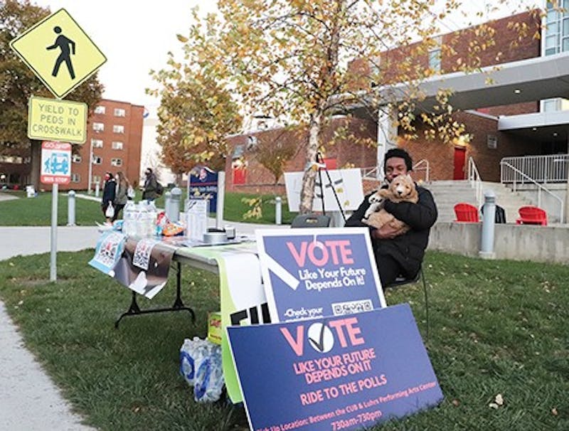 Eyoel Delessa and his dog, Nike, sit at the ShipVotes’ table outside the Ceddia Union Building (CUB) with voter transportation and election information.