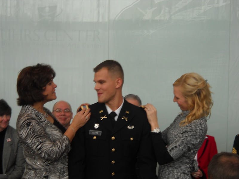 	William Lloyd has his new Second Lieutenant Rank placed up his shoulders by his mother Suzanne Lloyd and his fiancée Janelle Weller.