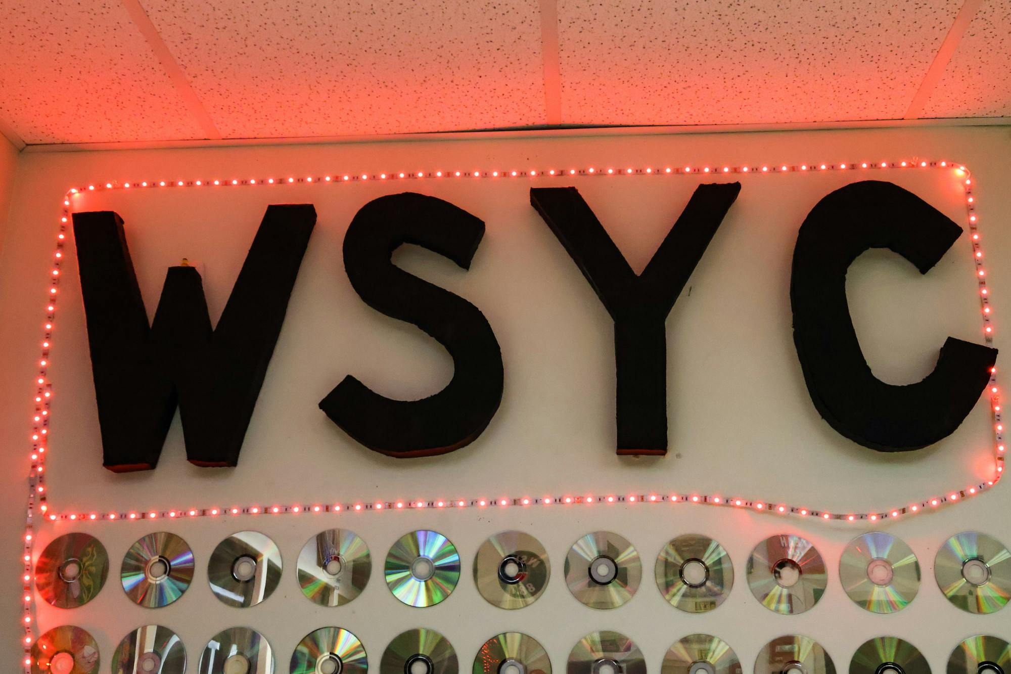 "We Serve Your Community." WSYC letters in studio's office.