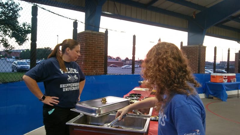 Campus police officers serve hamburgers and hot dogs to students Tuesday evening at their annual picnic.