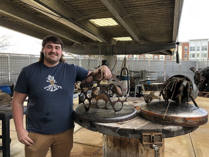 Colby Page poses with his two metal sculptures.