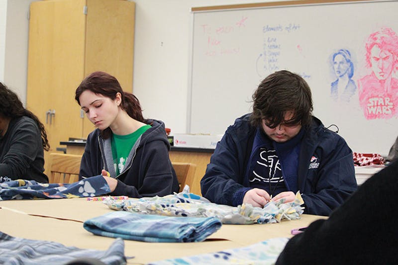 Art club members make tie fleece blankets to donate to an animal shelter.