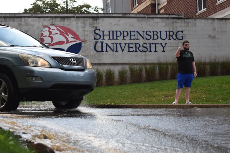 Marcus Webb, resident assistant, helps direct traffic as Adams Drive floods from busted water main behind Naugle Hall.