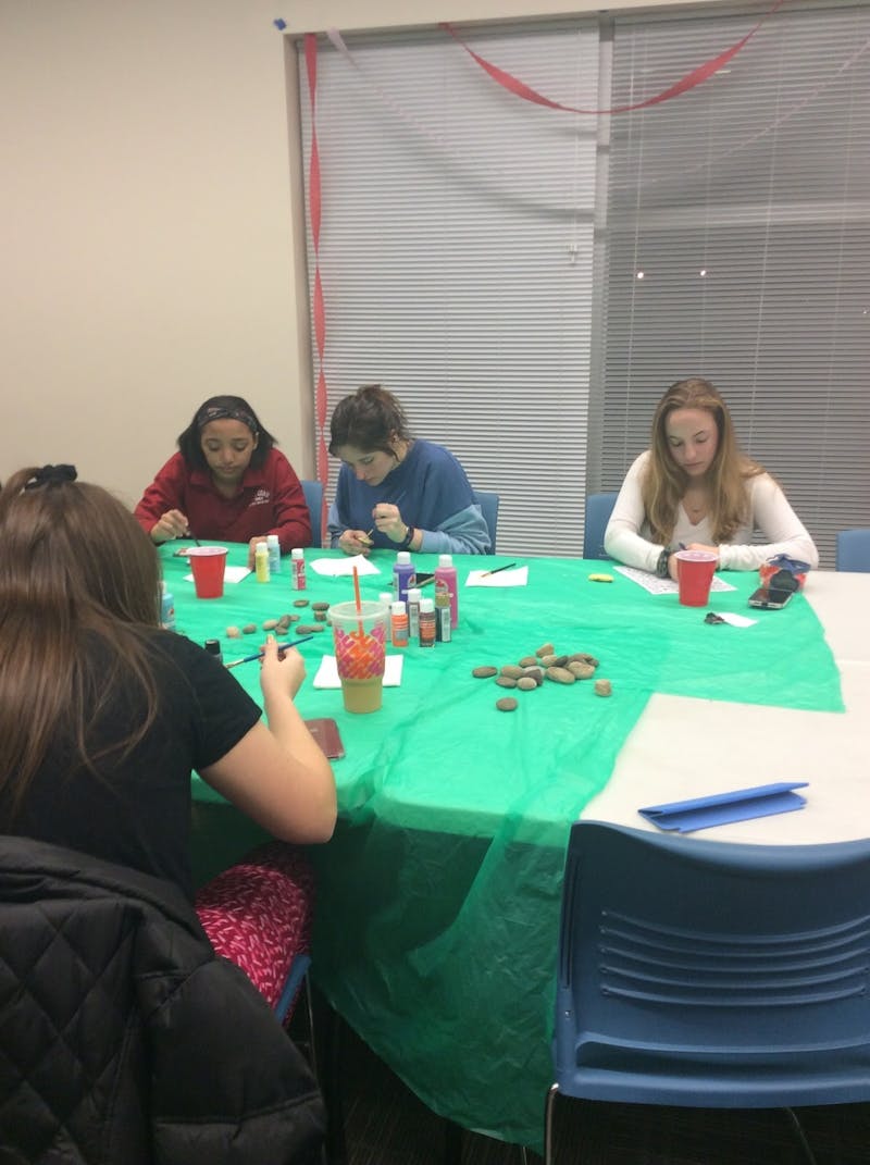 Students paint rocks to relieve anxiety and enjoy a night of tarot cards and music at the wellness event.