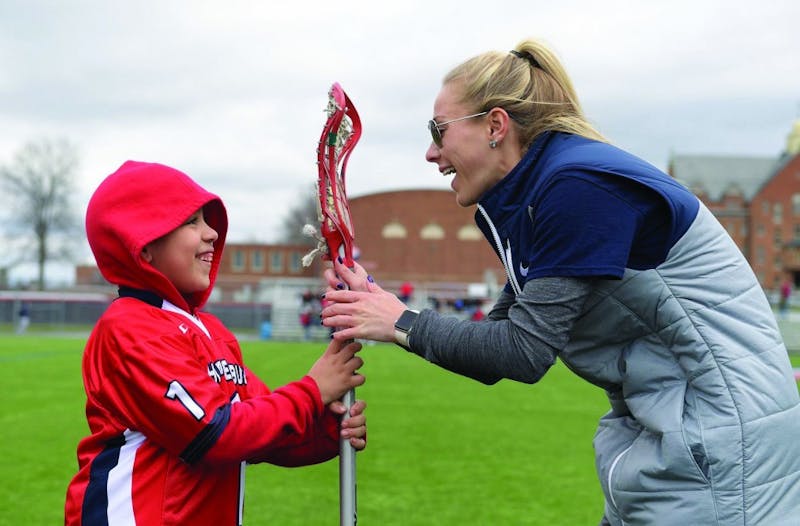 SU head coach Nicole Miller, right, presents Jay Dawson, left, with a lacrosse stick before Saturday’s game against IUP.&nbsp;