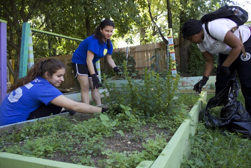 Left to right) Students Emily Gregorski, Paige Deon and Danita Dalton weed the garden at one of the Silence of Mary homes in Harrisburg. A group from SU comes each year to volunteer.