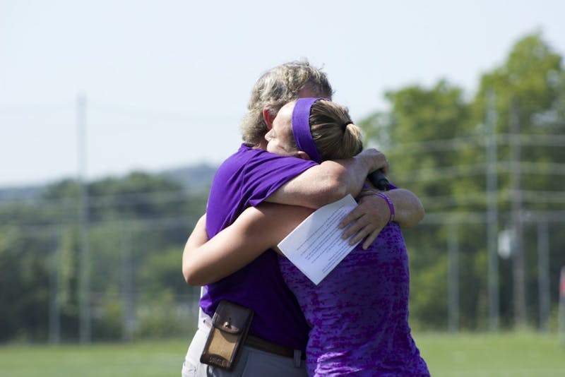 Head coach Bertie Landes hugs Katie Shoop, former teammate of Strous', after Shoop spoke about Strous' impact on her life.