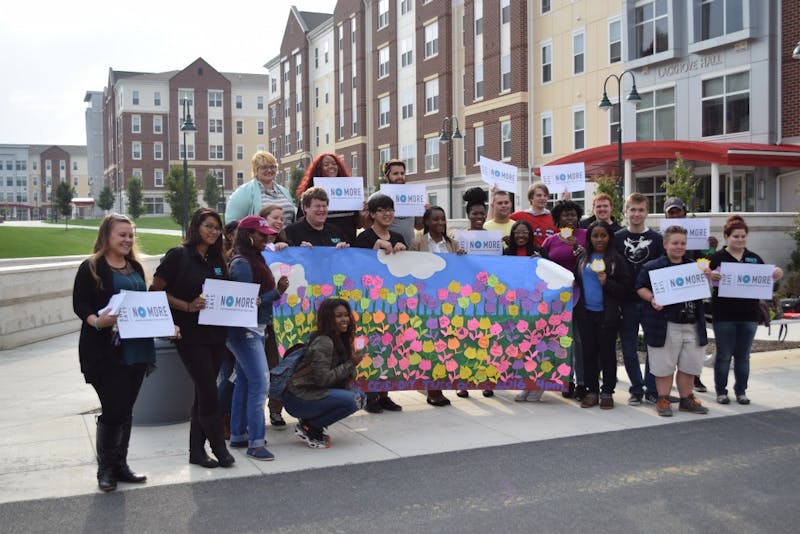 Students gather and hold signs to honor the victims of domestic violence