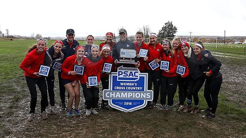 Members of the women’s cross country team celebrate after winning the 2018-2019 PSAC championship.
