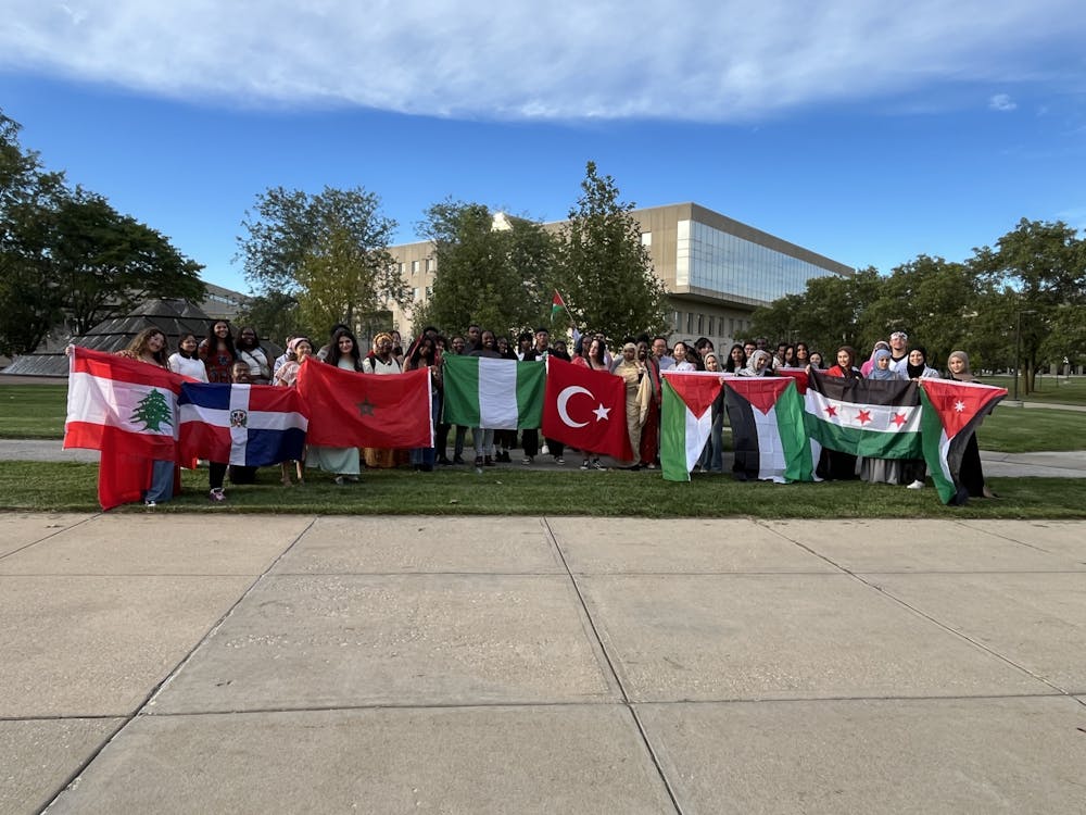 <p>Students pose with their cultural flags outside the Wood Fountain during the parade.</p>