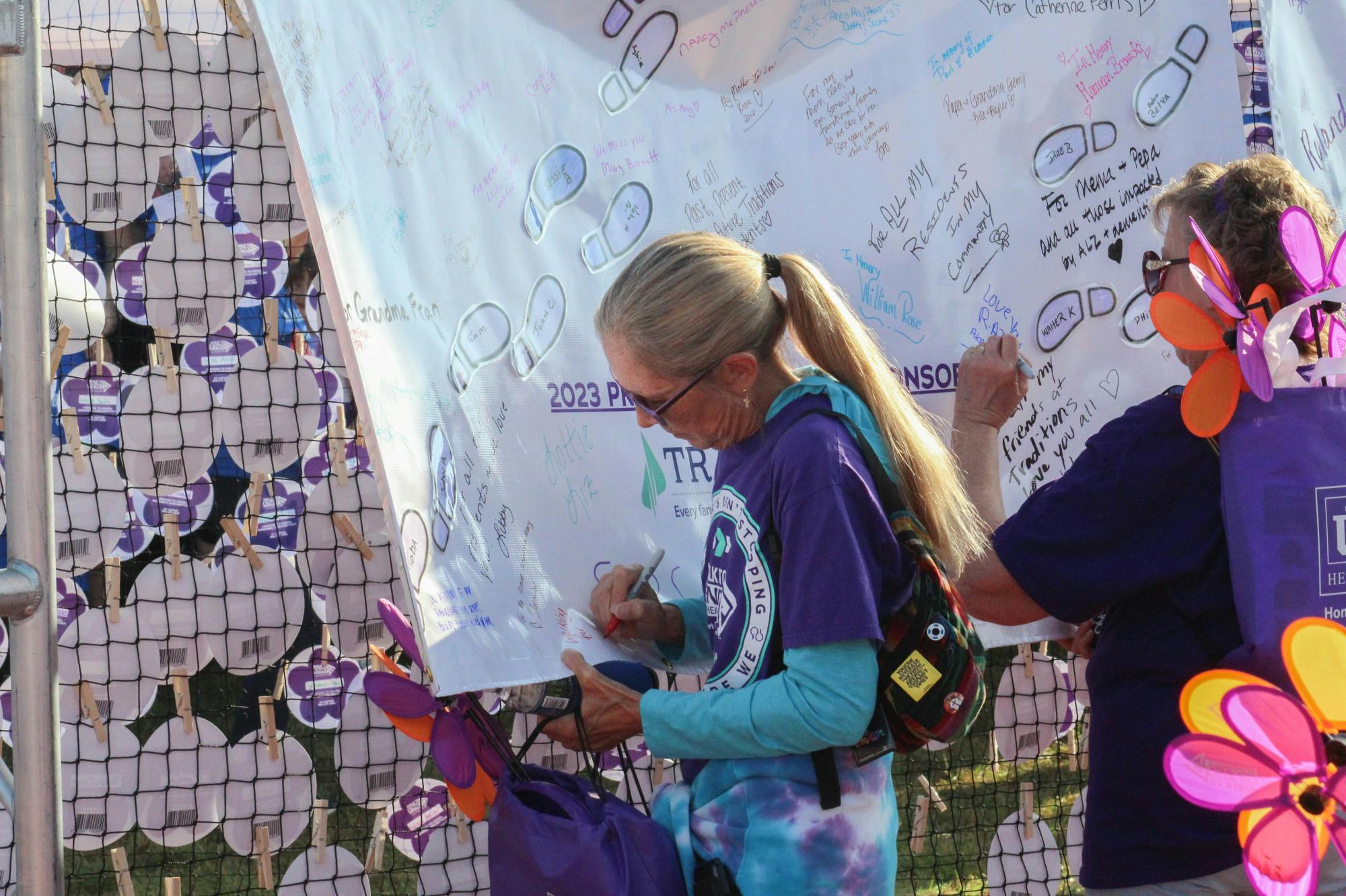Participants sign a banner, dedicating their donations to loved ones 