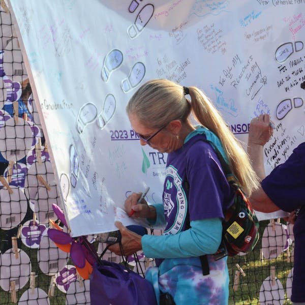 Participants sign a banner, dedicating their donations to loved ones 