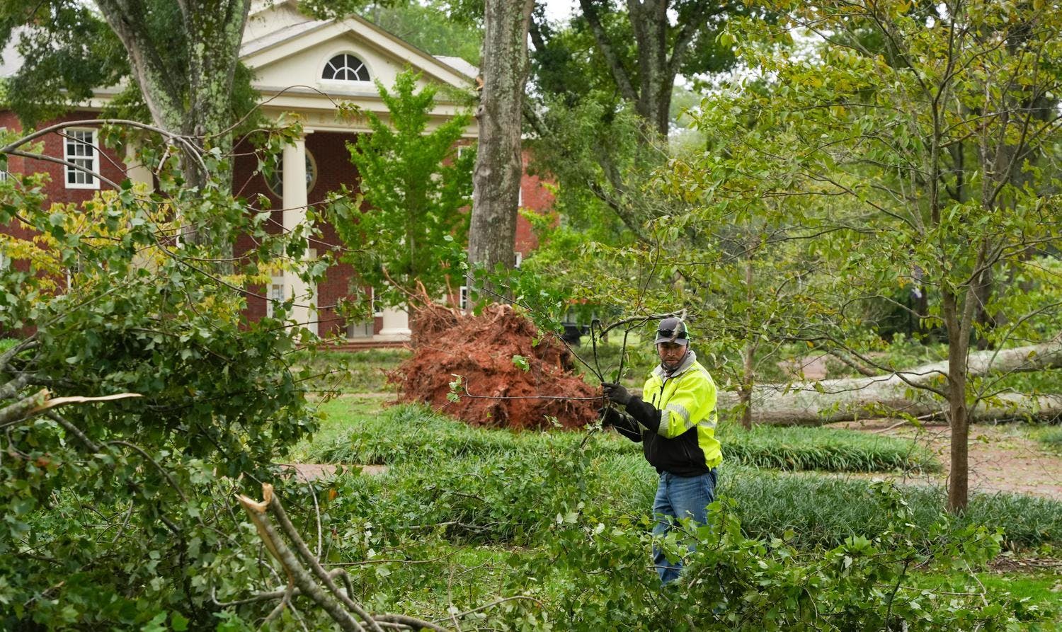A worker picks up branches on Furman University's campus after Hurricane Helene.