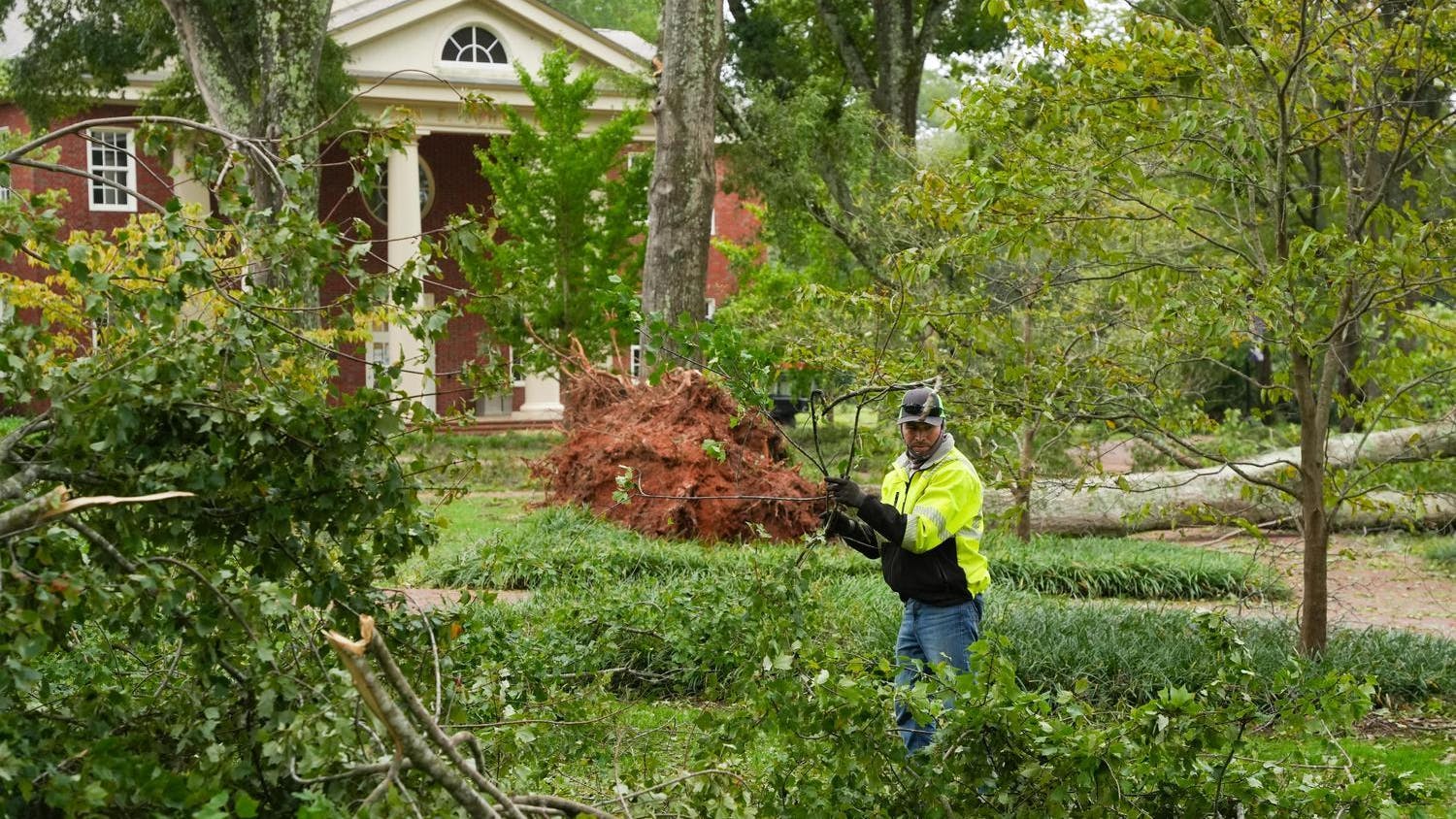 A worker picks up branches on Furman University's campus after Hurricane Helene.