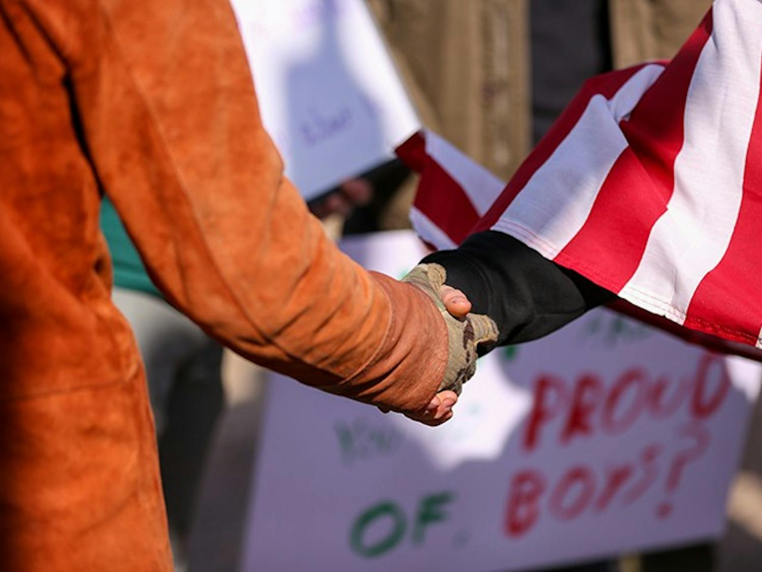 A member of the “Drive4America” caravan (right) shakes hands with a counter-protester (left) after the two groups met and voiced their frustrations.&nbsp;